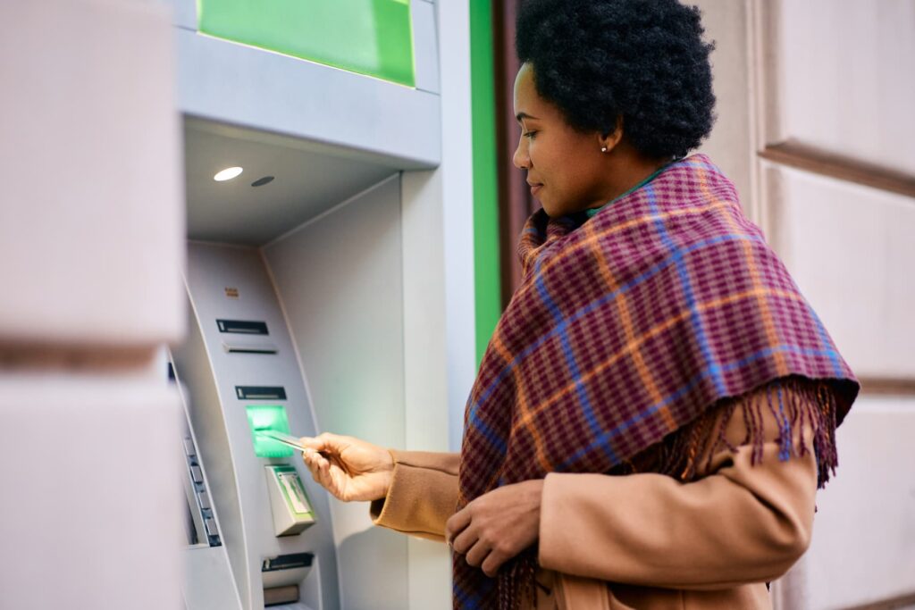 Афроамериканка знімає гроші з банкомату.